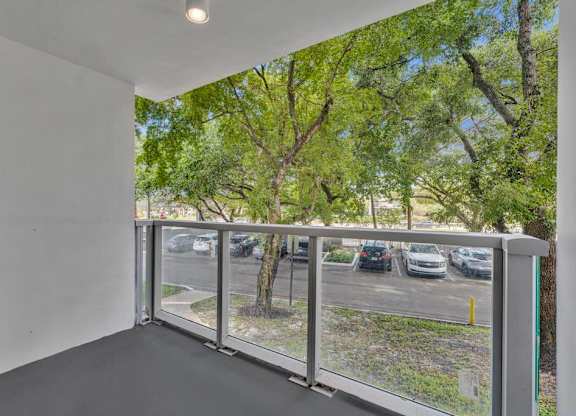A balcony with a view of a parking lot and trees.