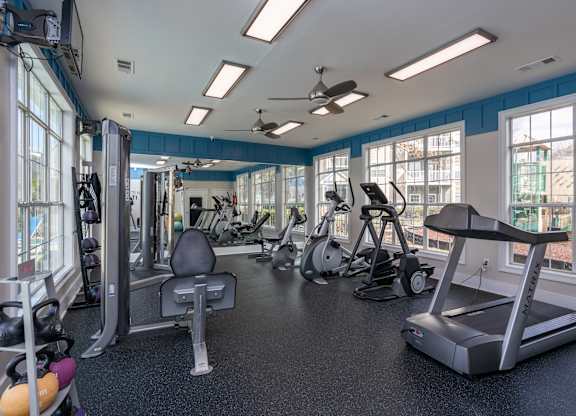 a gym with cardio machines and other exercise equipment and windows