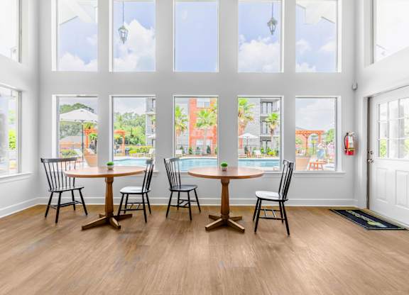 A dining room with a table and chairs in front of a large window.