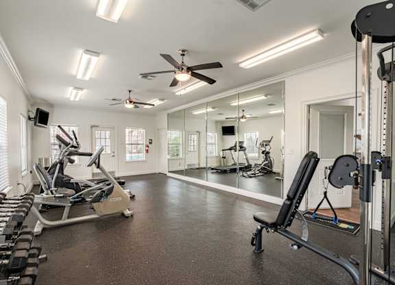 A spacious home gym with a variety of equipment including treadmills, weights, and a mirrored wall.