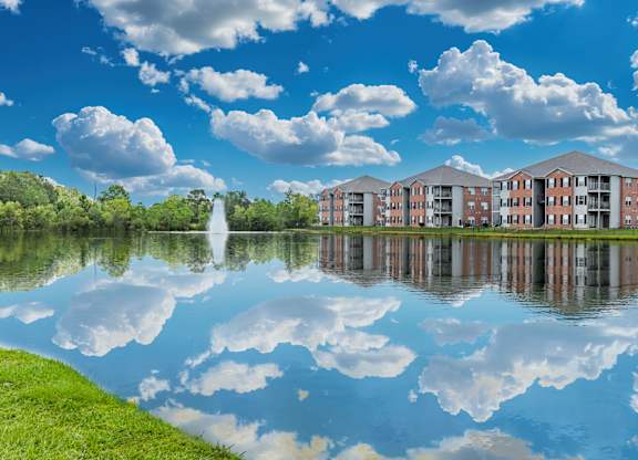 A serene lake with a building in the background and clouds in the sky.