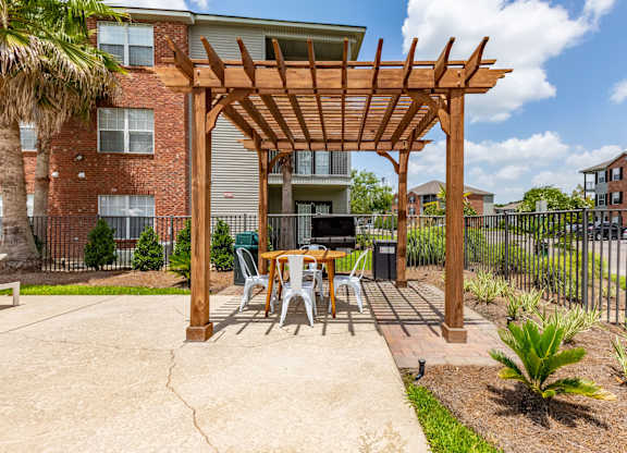 A wooden pergola is over a table set for four.