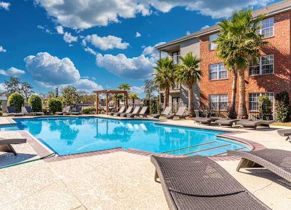 A large swimming pool surrounded by lounge chairs and palm trees.