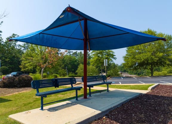 two benches with an umbrella on a sidewalk