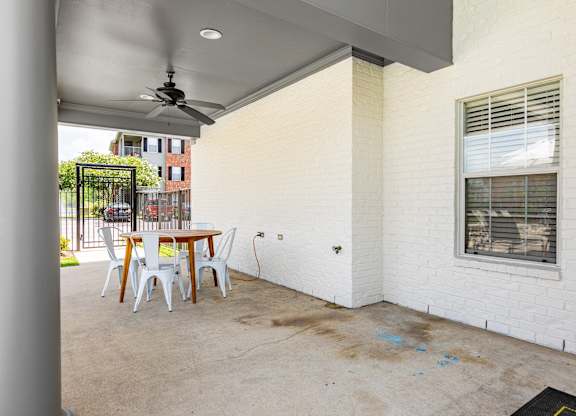 A patio with a table and chairs is covered by a roof.