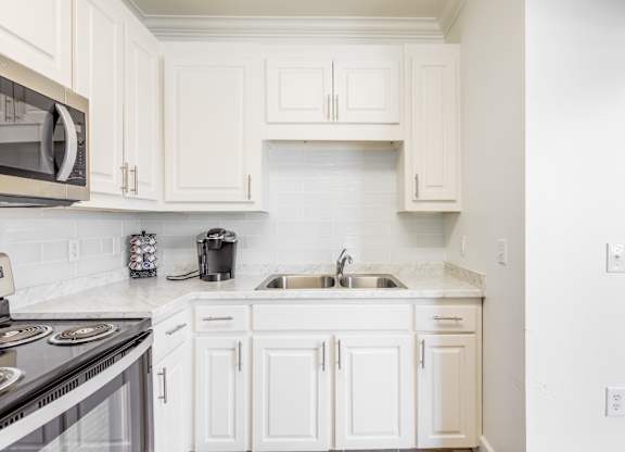 A kitchen with white cabinets and a black stove top.