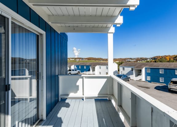 a covered balcony with a view of a parking lot and blue buildings