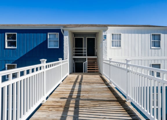 a blue and white house with a porch and a boardwalk