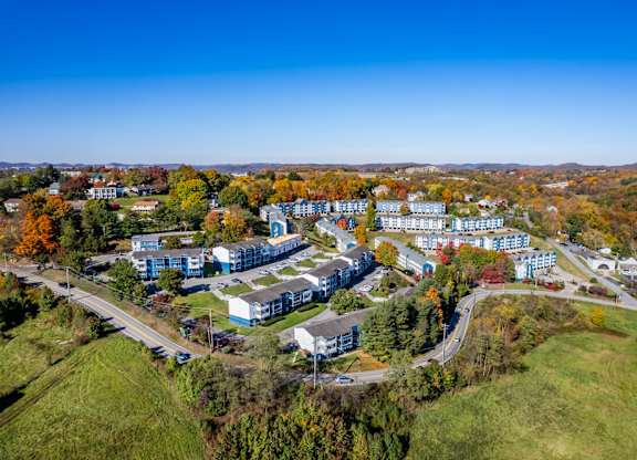 An aerial view of a large building complex surrounded by trees in autumn colors.