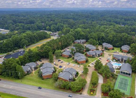 A bird's eye view of a residential area with houses, a tennis court, and a parking lot.