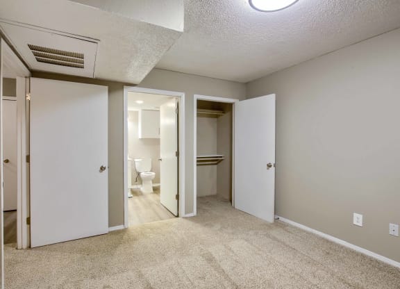 a bedroom with two closets and a bathroom in the background