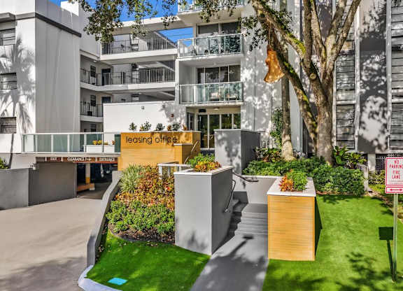 A leasing office is located in a modern building with a landscaped area in front.