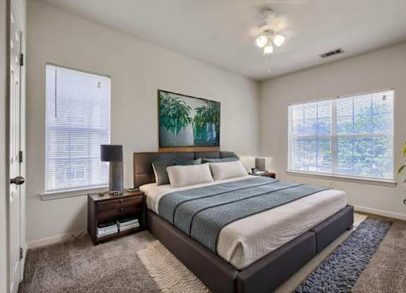 A bedroom with a large bed, a nightstand with a lamp, and a painting on the wall.