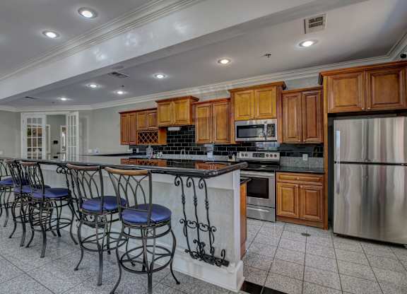 A kitchen with wooden cabinets and a bar area with blue stools.