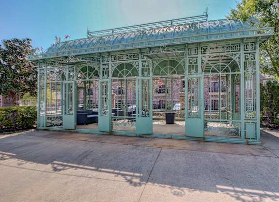 A green metal structure with a glass roof and arched windows.