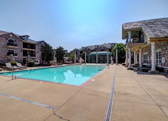A large swimming pool in front of a building with a sunny day.
