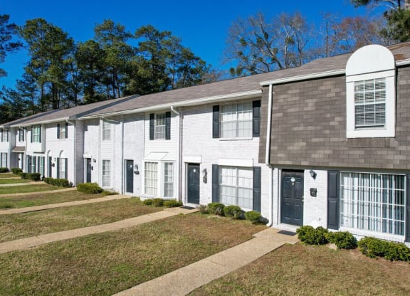 a row of white houses with black doors and a sidewalk