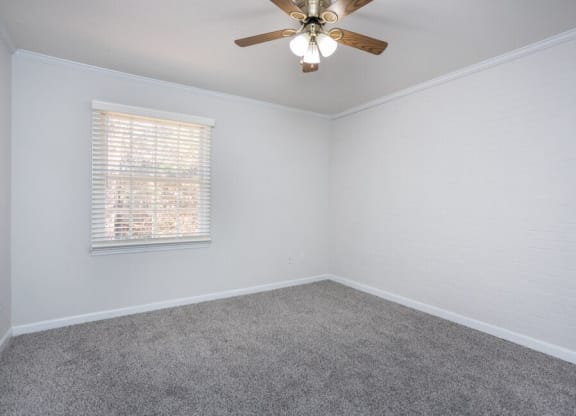 an empty bedroom with a ceiling fan and a window