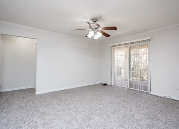 an empty living room with a ceiling fan and a window