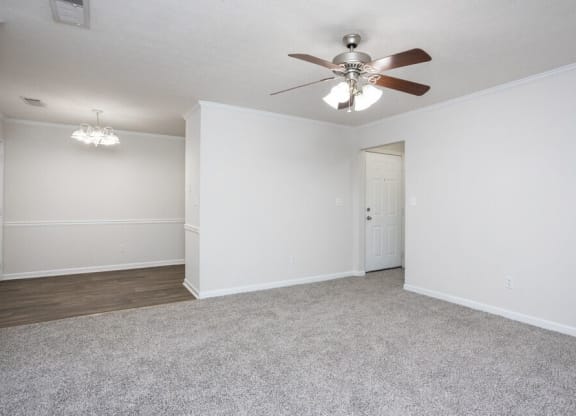 an empty living room with a ceiling fan