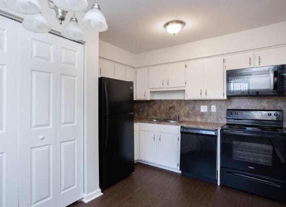 a kitchen with black appliances and white cabinets
