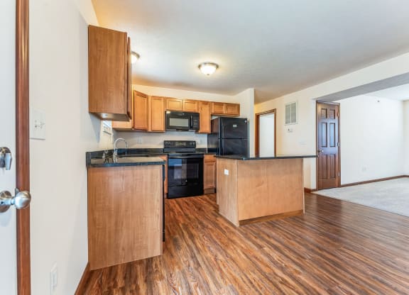 the view of a kitchen and living room with wood flooring