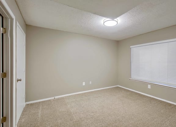 a bedroom with a large window and beige carpet