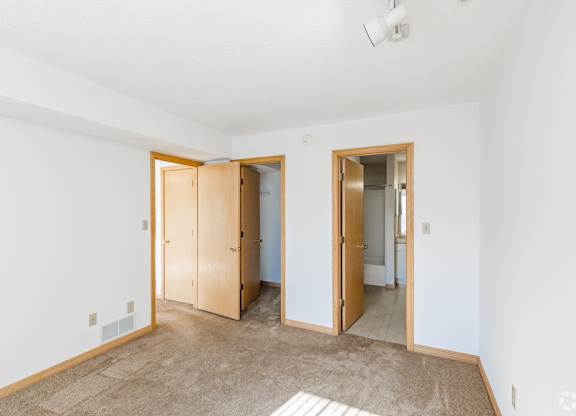 A room with a carpeted floor and two open doors.