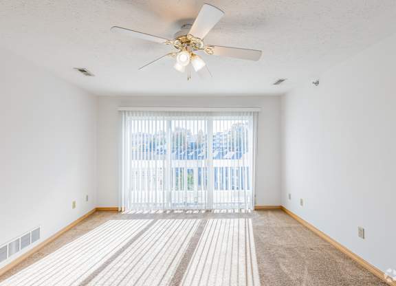 A room with a ceiling fan and a carpeted floor.