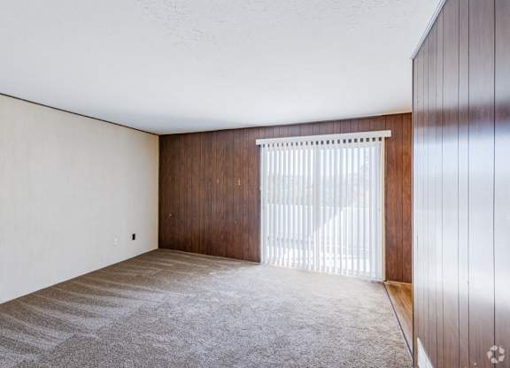 A room with a carpeted floor and a wooden door.