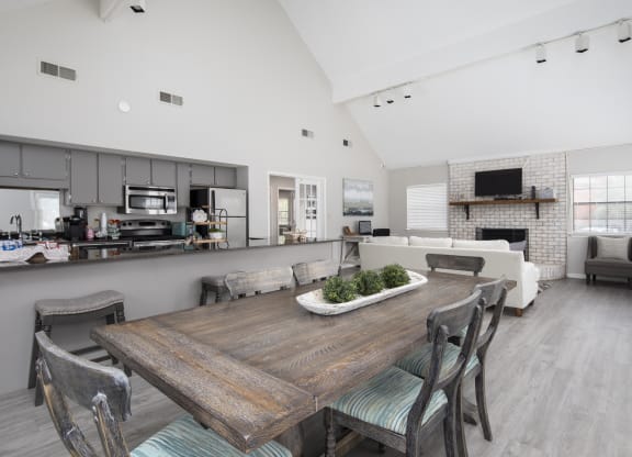 a dining area with a wooden table and chairs and a kitchen in the background