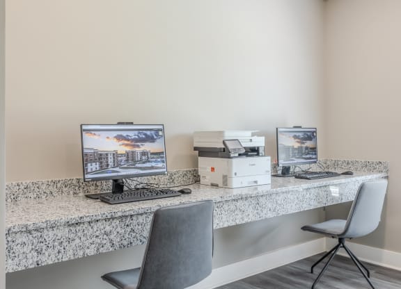 a office with two computers and a printer on a desk