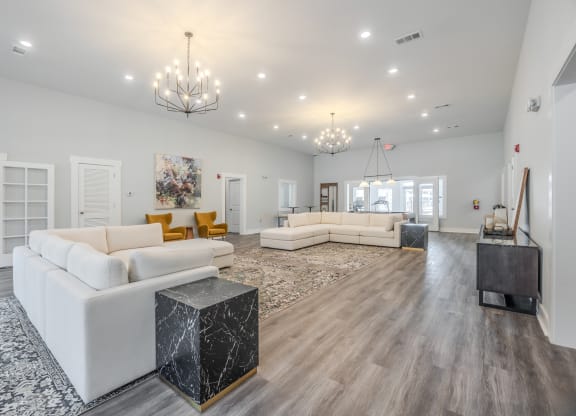a living room with couches and a rug and chandeliers