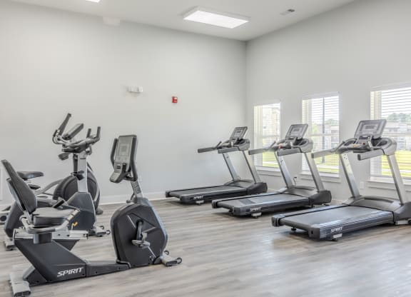 a gym with several treadmills and ellipticals on the floor