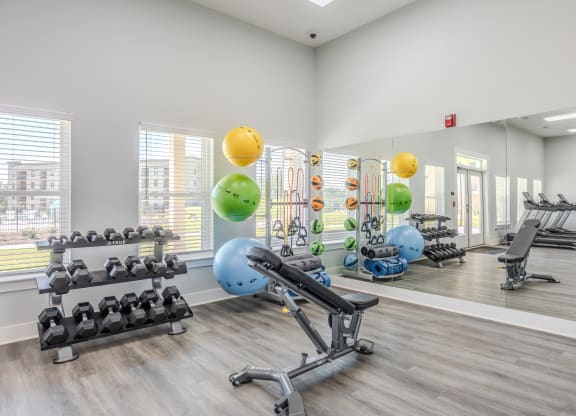 a gym with exercise equipment and weights on the floor and a large window