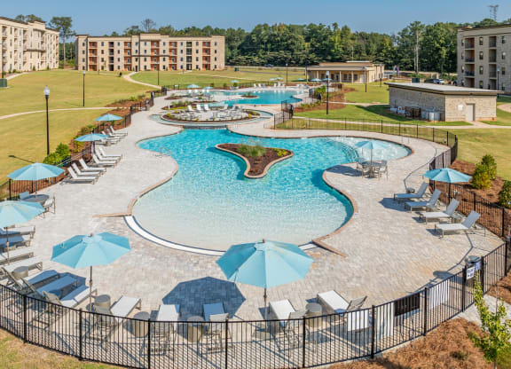 an aerial view of a large swimming pool with umbrellas and chairs around it