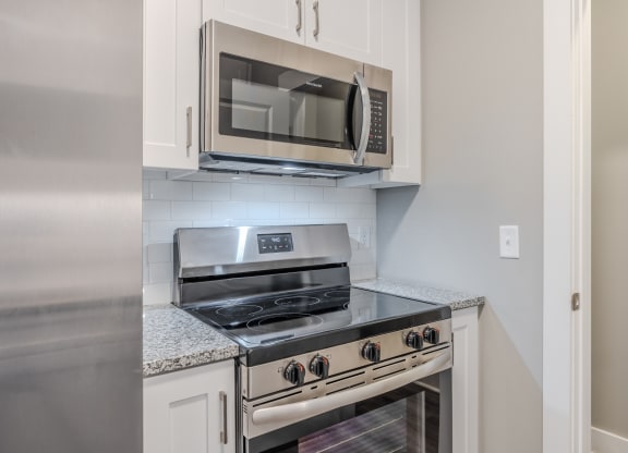 a kitchen with white cabinets and a stove and microwave