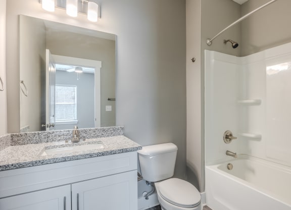 a bathroom with a toilet sink and shower and a mirror