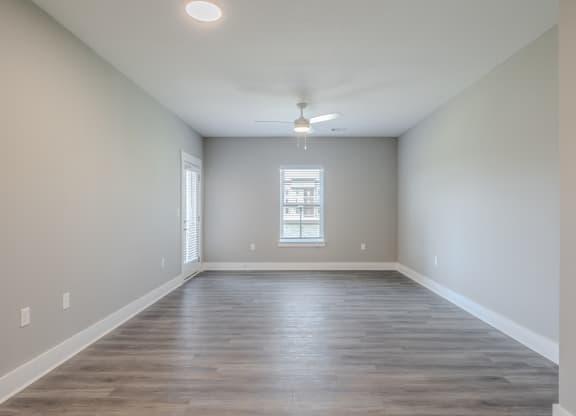 an empty living room with wood floors and a window