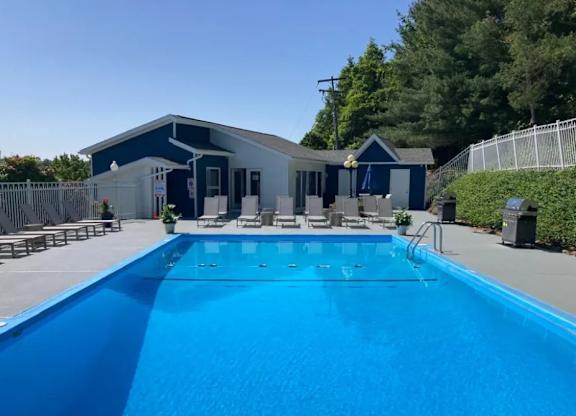 A blue swimming pool in front of a house.