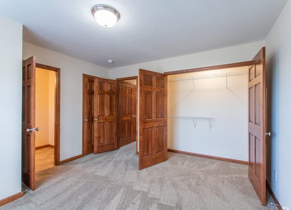 an empty bedroom with wooden doors and a carpeted floor