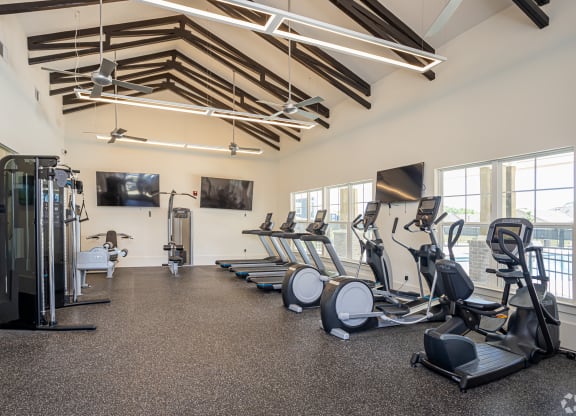 a gym with cardio equipment and windows on the wall