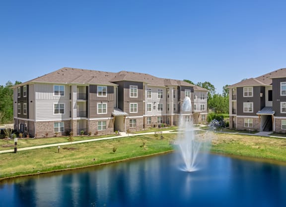 a fountain in a pond with an apartment building in the background