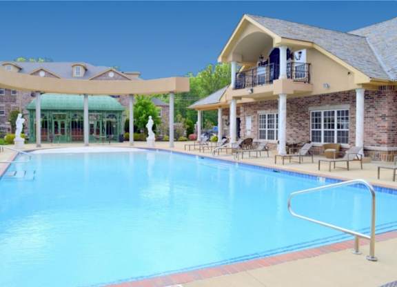 A large swimming pool in front of a building with a balcony.