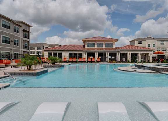 A large swimming pool in front of a building with a red roof.