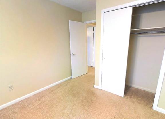 A room with a carpeted floor and two white doors.