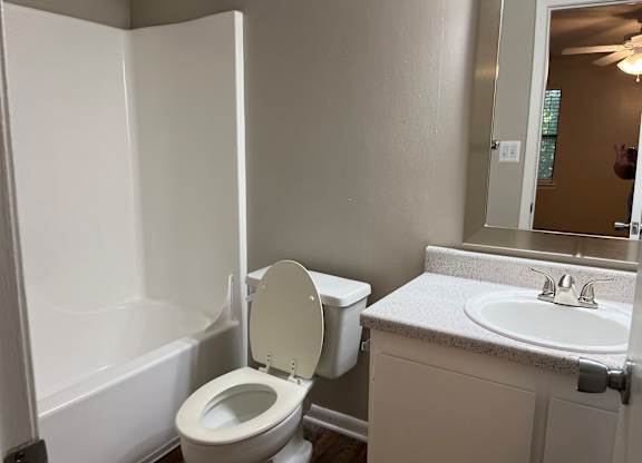 A white toilet is in a bathroom with a white sink.