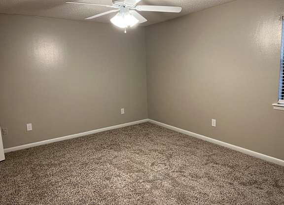 A room with a ceiling fan and carpeted floor.