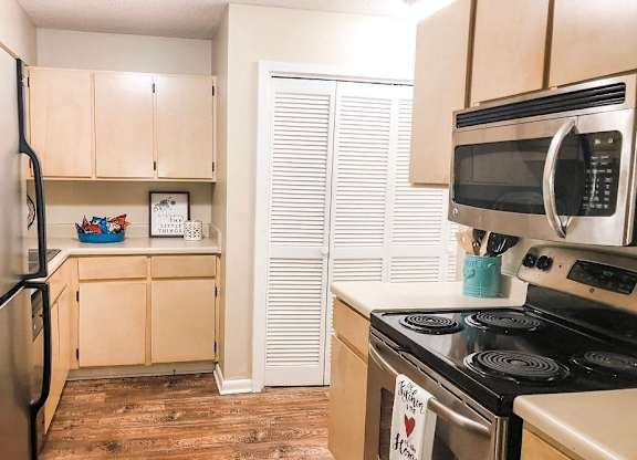 A kitchen with a refrigerator, stove, and microwave.