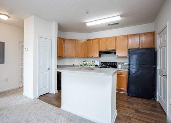 an empty kitchen with an island and black refrigerator